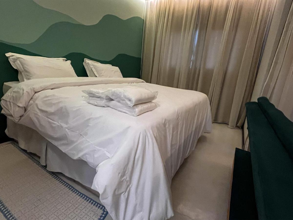 Suíte Esmeralda — detalhe da cama e cabeceira verde