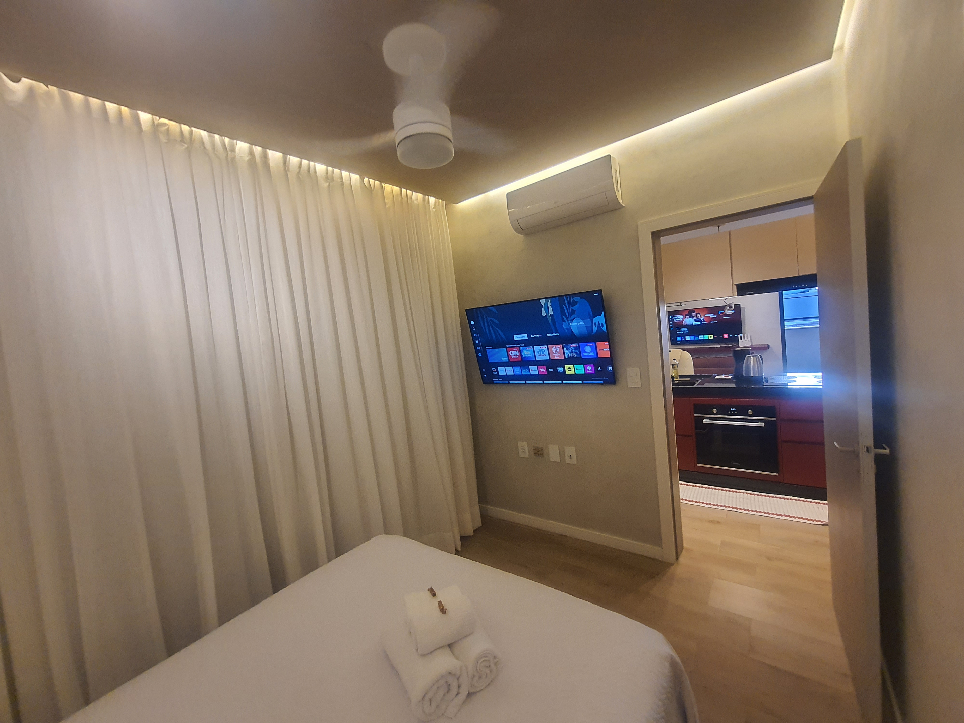 Quarto com Smart TV e vista para cozinha integrada